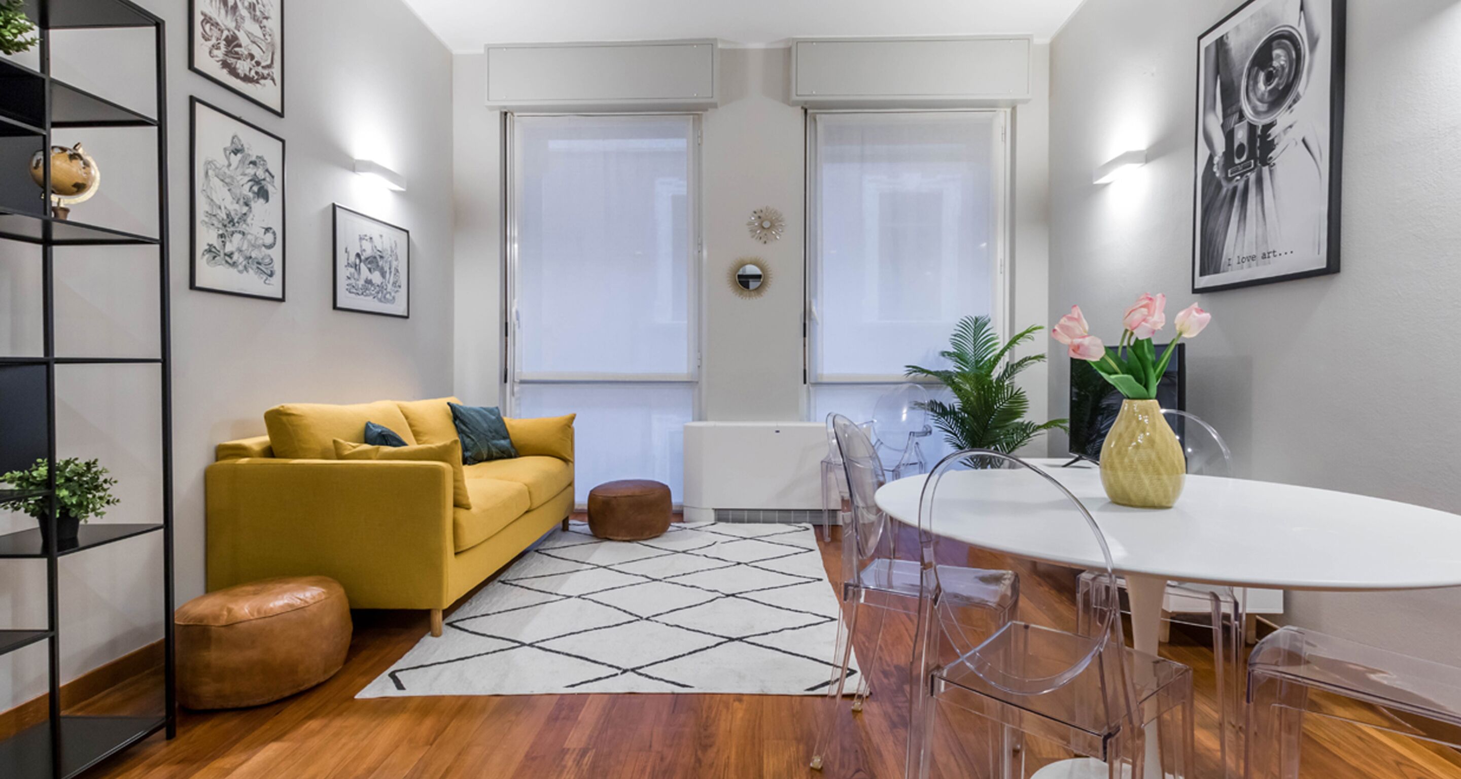 Un salon moderne avec un canapé jaune, une table ronde et un coin repas dont le plateau est en verre transparent.