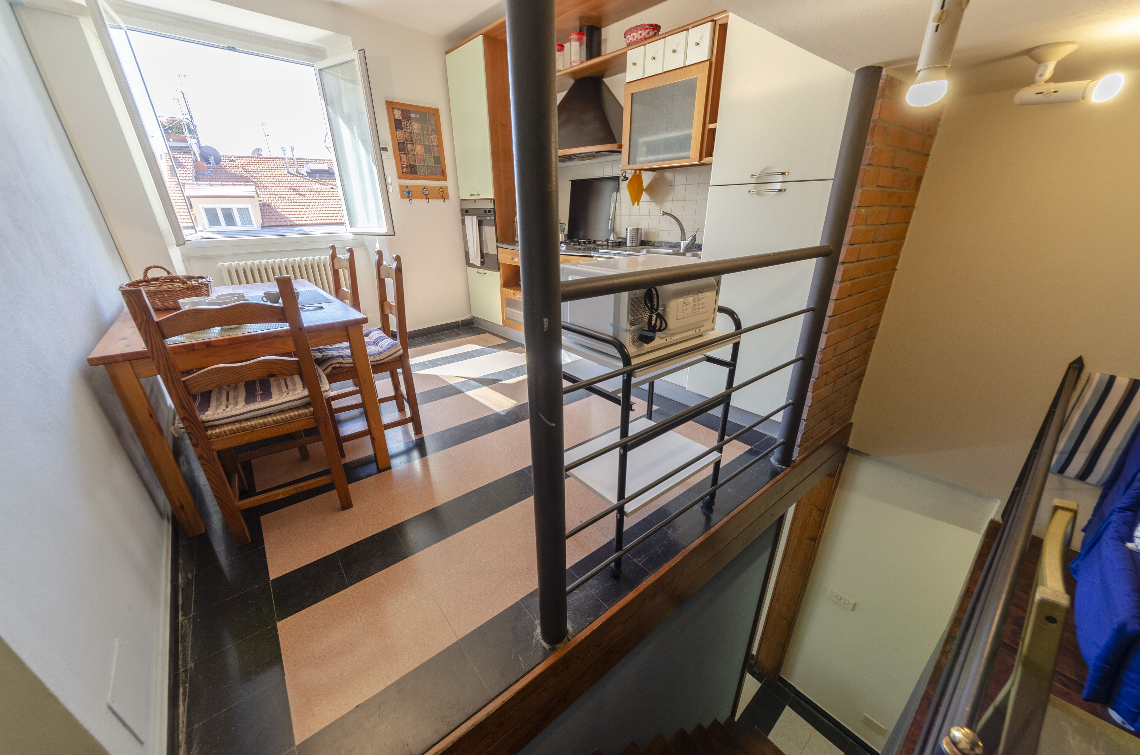 Une cuisine avec une table et des chaises, une fenêtre et un escalier.