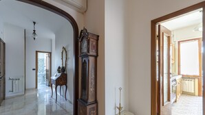 A spacious hallway with a large grandfather clock, a small table with a candle, and a view into another room. - JOIVY Front Sea Apt With Big Terrace In Chiavari (Chiavari)