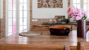 A wooden dining table with a placemat, a brown ceramic pot, and a vase with flowers. - JOIVY Superb Villa For 7 W/Backyard And Bbq Area In Vaccarezza (Bobbio)