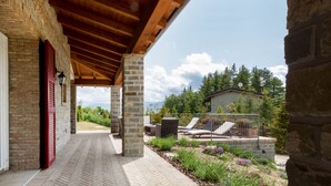 A covered patio with stone pillars, a brick wall, and a view of a mountain and trees. - JOIVY Superb Villa For 7 W/Backyard And Bbq Area In Vaccarezza (Bobbio)