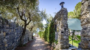 A stone pathway flanked by trees and stone walls, leading to a stone structure with a light fixture. - JOIVY Villa W/Superb View And Private Garden In Mulinetti (Recco)
