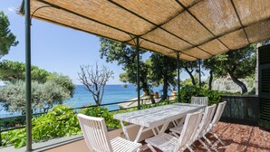 A covered outdoor seating area with a table and chairs, overlooking a scenic view of the sea and greenery. - JOIVY Villa W/Superb View And Private Garden In Mulinetti (Recco)
