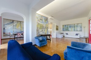 A spacious living room with a wooden floor, blue armchairs, a white sofa, and large abstract paintings on the walls. - JOIVY Apt W/Amazing Sea View And Patio, Next To Port Of Rapallo (Rapallo)