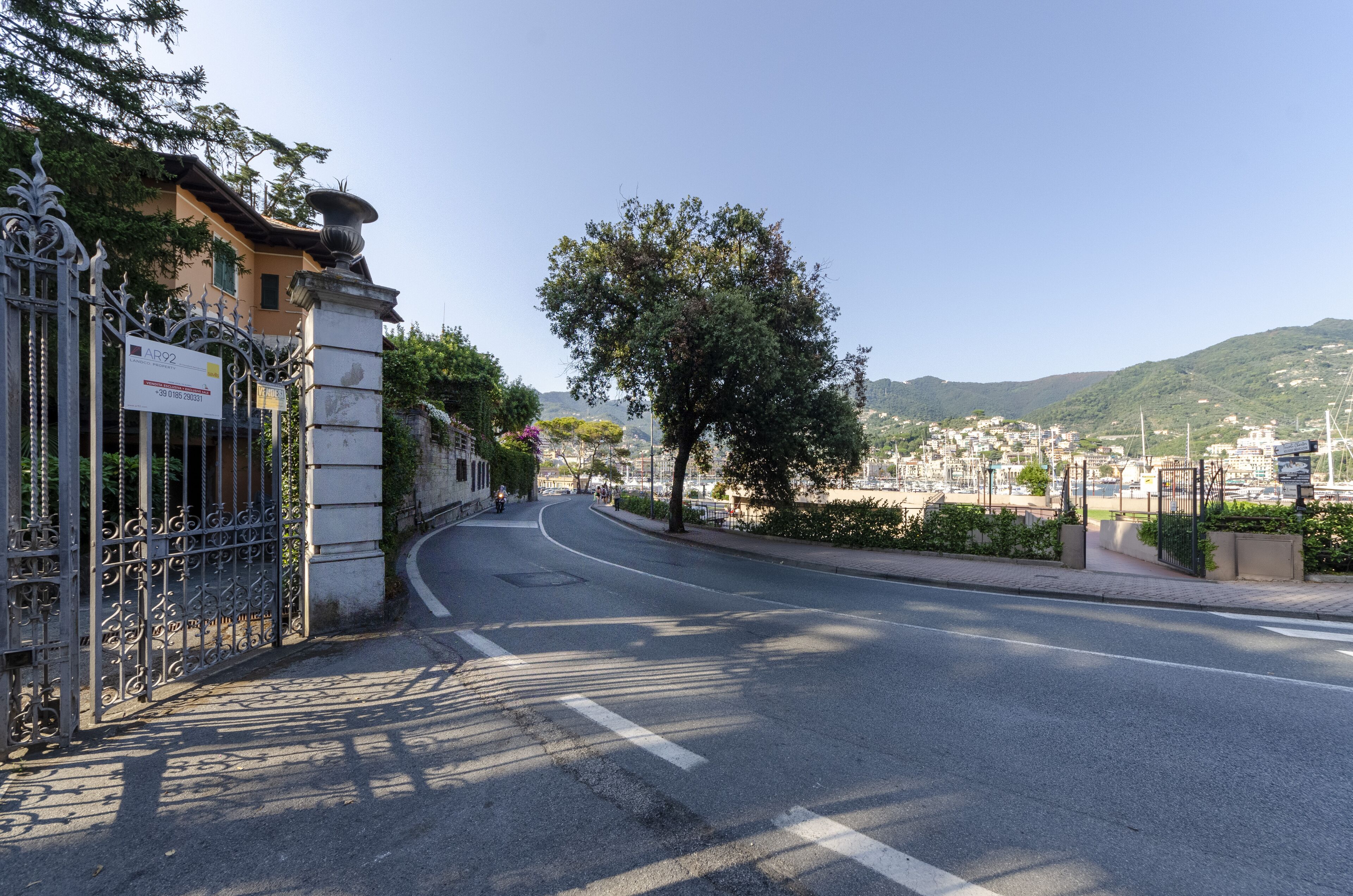 A street leading to a building with a metal gate and a signboard.
