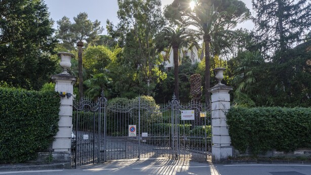 A gated entrance with a metal fence and two stone pillars, surrounded by lush greenery and trees. - JOIVY Apt W/Amazing Sea View And Patio, Next To Port Of Rapallo (Rapallo)