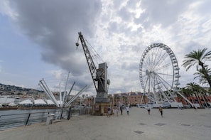 A waterfront promenade with a large Ferris wheel and a crane structure. - JOIVY Warm Family Flat For 9, Near Porto Antico (Genoa)