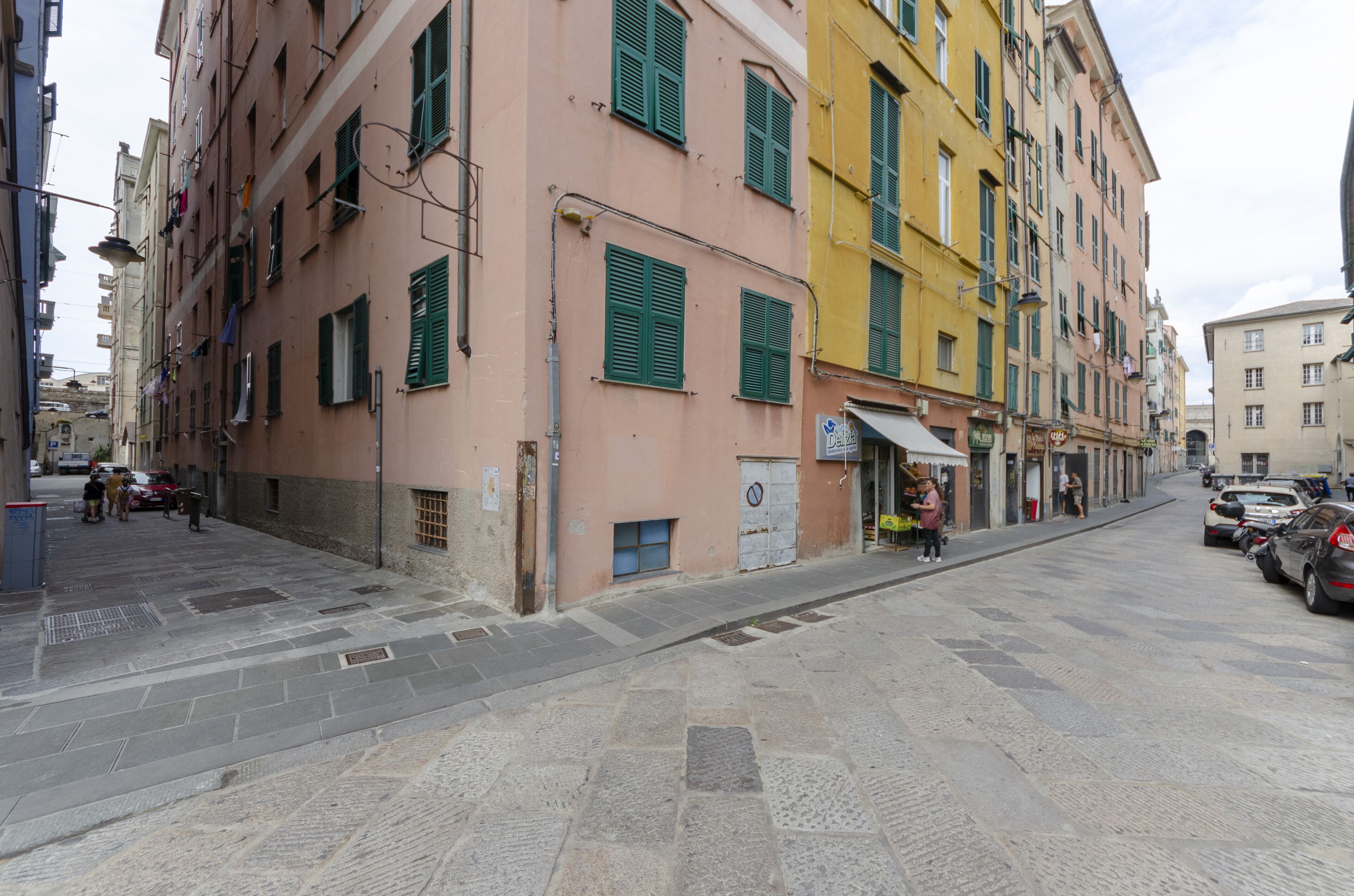 A narrow street with multi-story buildings, some with visible ground-floor shops.