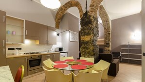 A modern kitchen with a dining area, featuring a stone column, a gas stove, and a microwave. - JOIVY Warm Family Flat For 9, Near Porto Antico (Genoa)