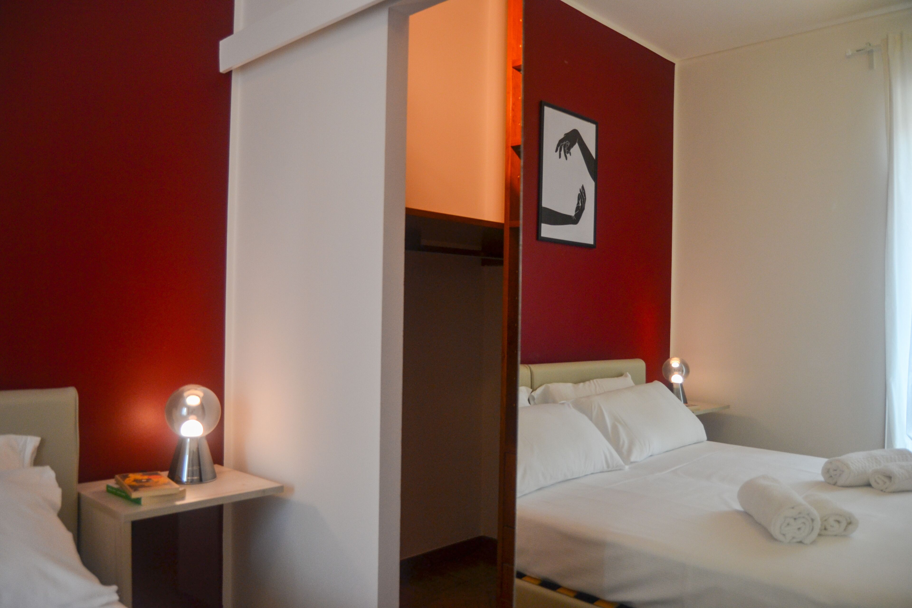 A hotel room with a bed, bedside table, and a nightstand with a lamp.