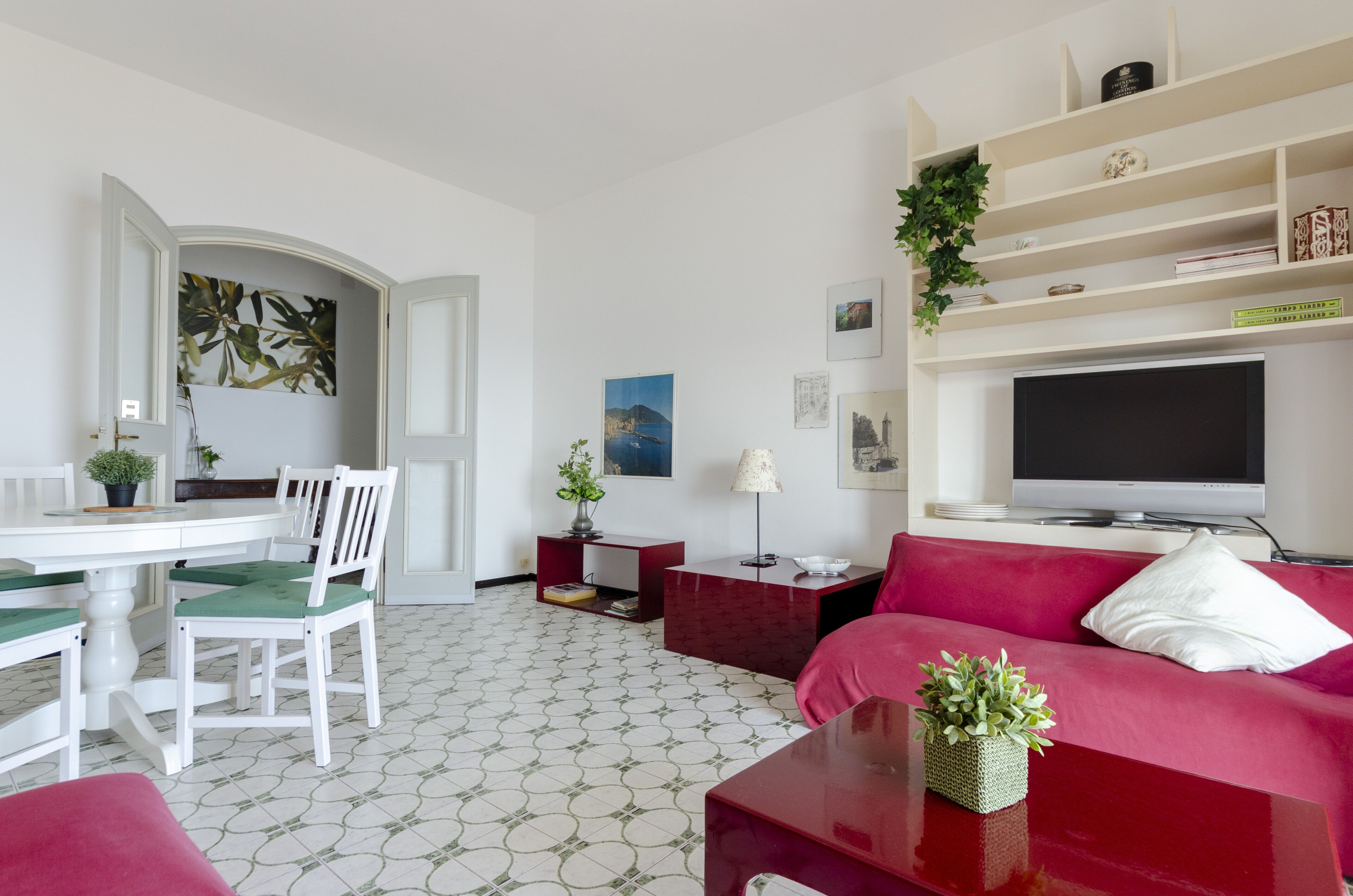 Een moderne woonkamer met een eetgedeelte, een flatscreen televisie en een rode bank.