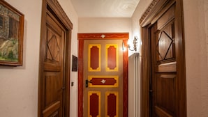 Un couloir avec des portes en bois, un radiateur et un tableau encadré accroché au mur.