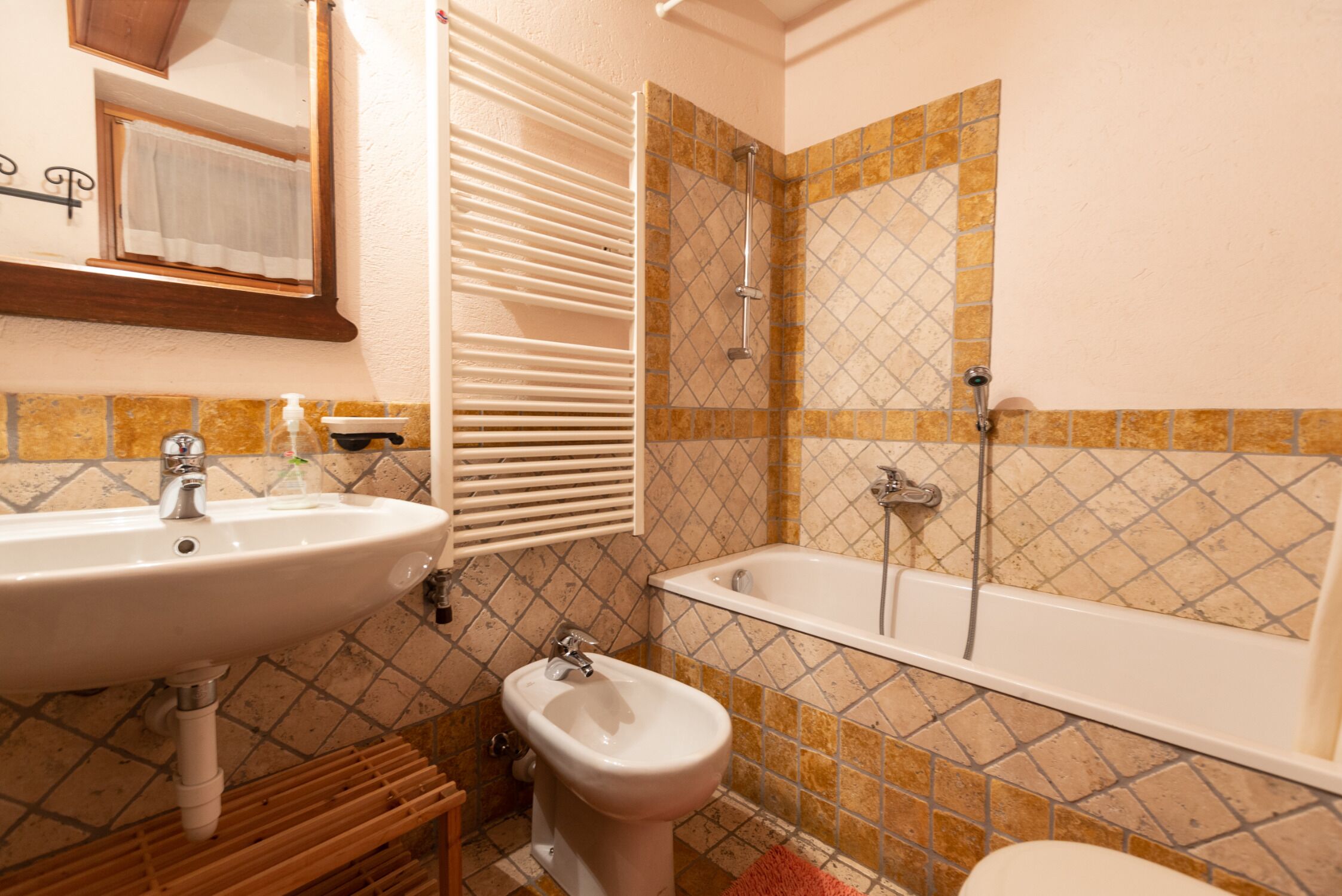A bathroom with a sink, bidet, and bathtub.