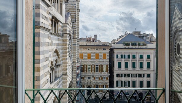 A view from a balcony overlooking a row of historic buildings with classical architecture, including columns and ornate details. - JOIVY Exclusive 3-bedroom flat near Cathedral of Genoa (Genoa)