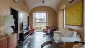 A modern hotel room with a balcony, a sofa, a table, and a TV. - JOIVY Exclusive 3-bedroom flat near Cathedral of Genoa (Genoa)