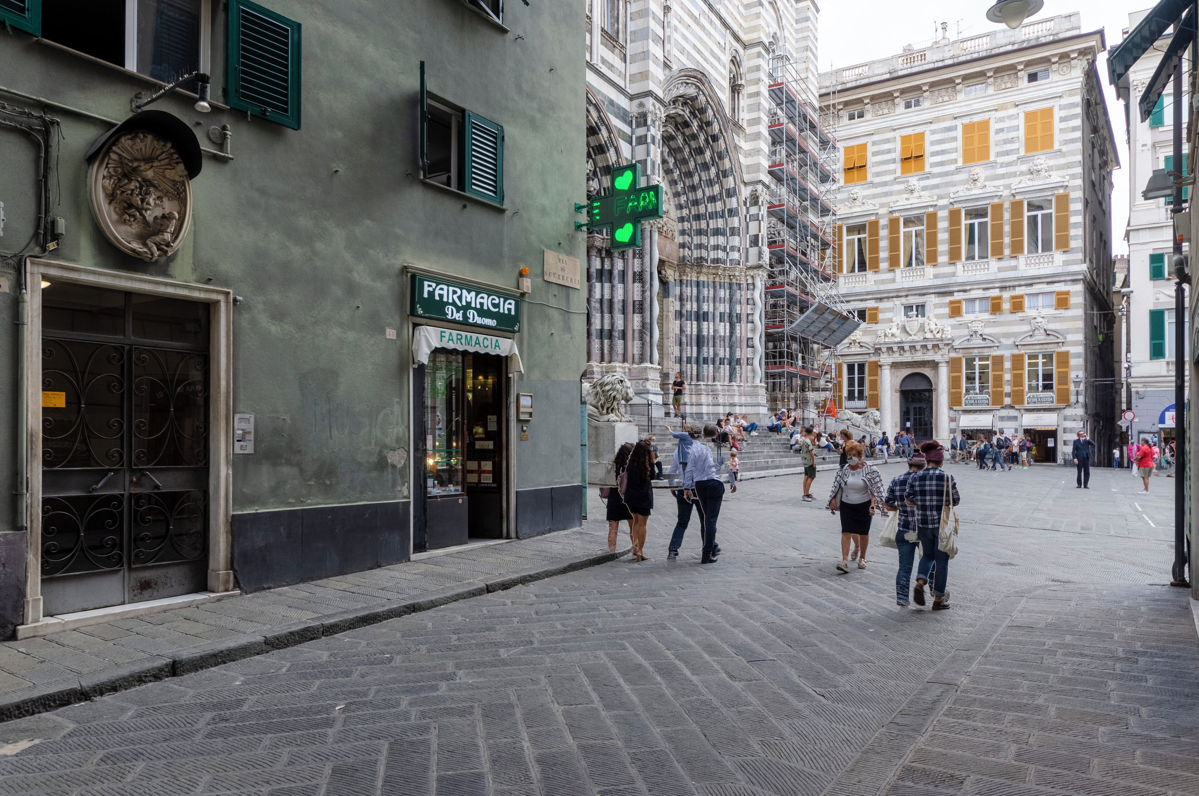 A cobblestone street with a pharmacy and ornate buildings.