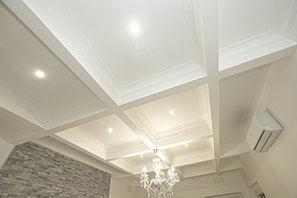 A room with a high ceiling, recessed lighting, a chandelier, and a stone accent wall.