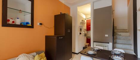 Una cocina compacta con refrigerador, una mesa de comedor para dos personas y una pequeña encimera.