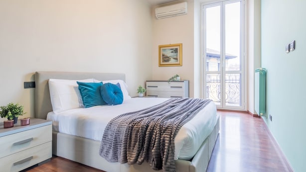 A bedroom with a bed, bedside tables, a radiator, a window with a view, and a painting on the wall. - JOIVY Elegant 1 Br Flat Next To Milano Centrale (Milan)