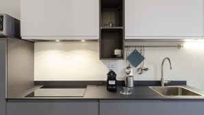 A modern kitchen with a built-in microwave, stainless steel sink, and a kettle. - JOIVY Elegant flat near Spianata Castelletto (Genoa)