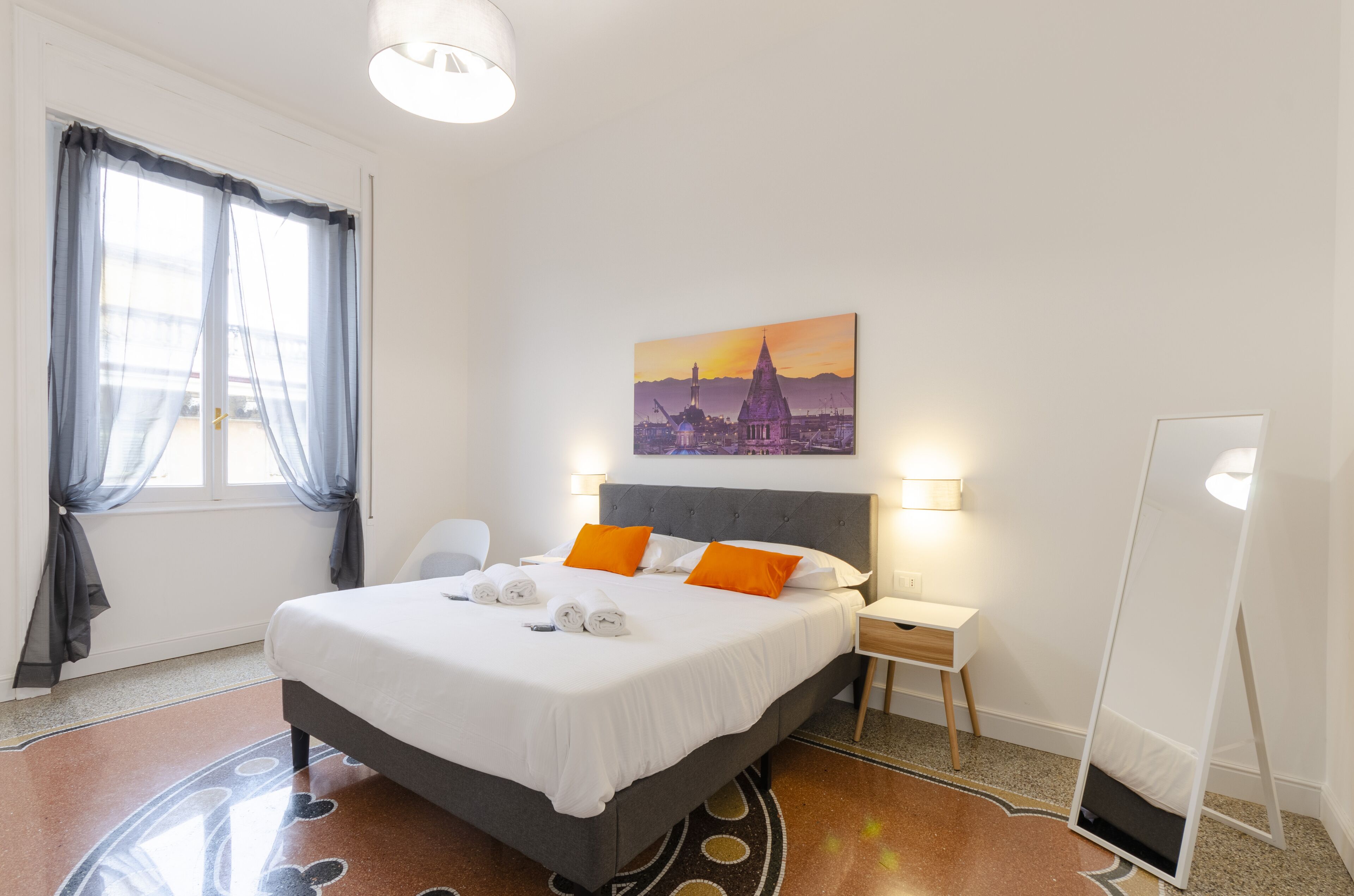 Ett välordnat hotellrum med en säng, sänglampor, ett skrivbord och en stor spegel.