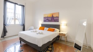 A neatly arranged hotel room with a bed, bedside lamps, a desk, and a large mirror. - JOIVY Elegant flat near Spianata Castelletto (Genoa)