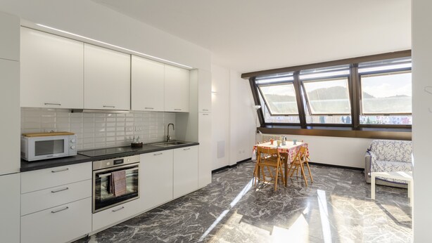 A modern kitchen with white cabinets, a microwave, and a dining area with a table and chairs.