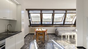 A modern kitchen with white cabinets, a black countertop, and a window overlooking a scenic view.