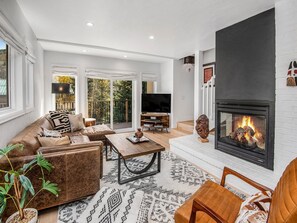 A modern living room with a fireplace, leather sofa, and a television. - Casolar Drive (Vail)