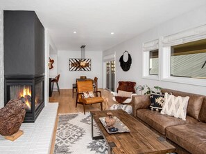 A modern living room with a fireplace, a dining area, and a sofa. - Casolar Drive (Vail)