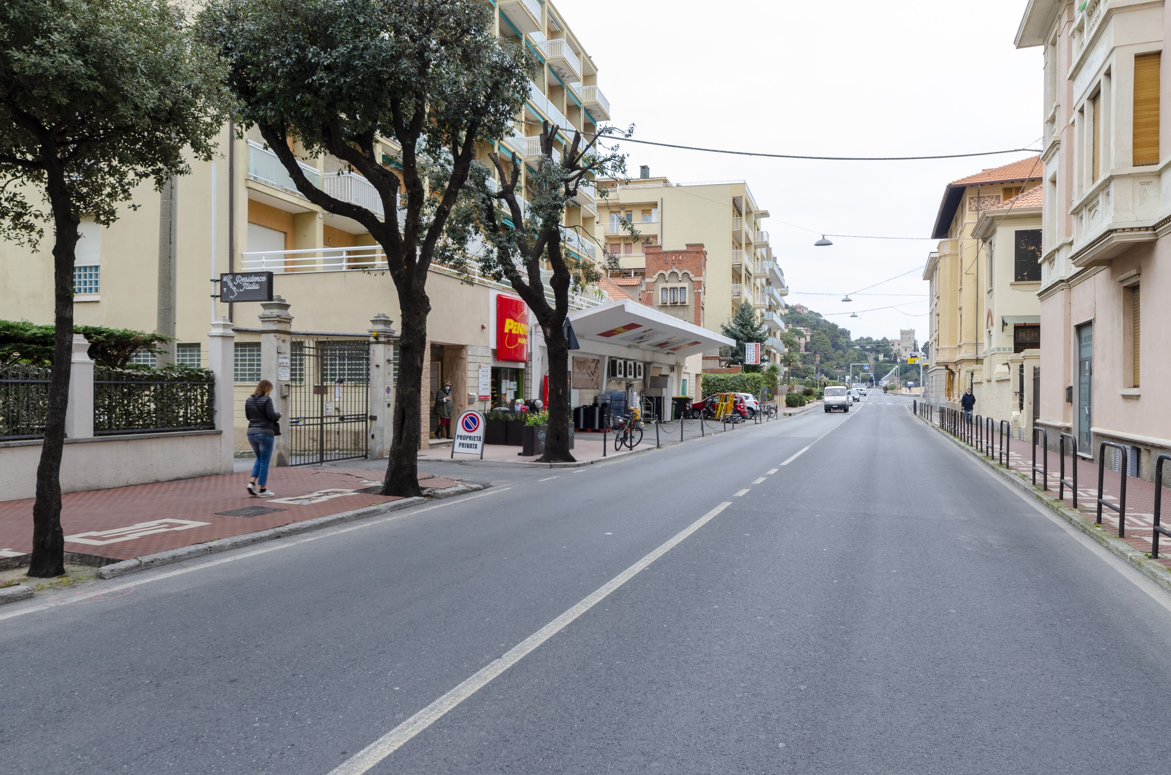 A street with buildings, a pedestrian, and a sign for a hotel.