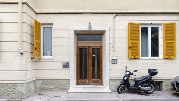 A building with a wooden door and yellow shutters, a scooter parked in front, and a number 47 sign on the wall. - JOIVY Family Apt For 6, Right Next To The Beach (Finale Ligure)