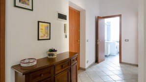 A hallway with a wooden cabinet, a framed picture, and a door leading to a laundry area. - JOIVY Family Apt For 6, Right Next To The Beach (Finale Ligure)