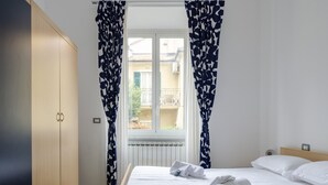 A bedroom with a bed, a wardrobe, and a window with curtains. - JOIVY Family Apt For 6, Right Next To The Beach (Finale Ligure)