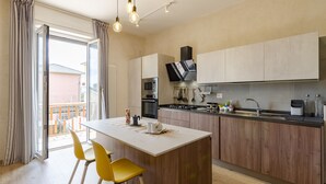 A modern kitchen with a central island, wooden cabinets, and a built-in oven. - JOIVY Chic Chiavari Apt With 2 Spacious Terraces (Chiavari)