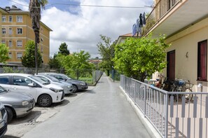Una fila de coches estacionados a lo largo de una calle flanqueada por edificios.