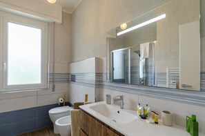 Un baño moderno con un espejo grande, un lavabo y un inodoro.