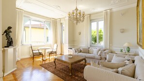 A spacious living room with a wooden floor, a chandelier, a sofa set, and a table. - JOIVY Splendid Villa With Orange Trees And Stunning View (Santa Margherita Ligure)