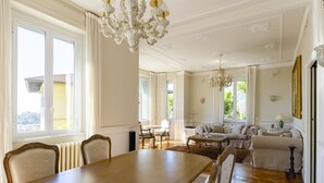 A spacious living area with a dining table, chairs, sofas, and a chandelier. - JOIVY Splendid Villa With Orange Trees And Stunning View (Santa Margherita Ligure)