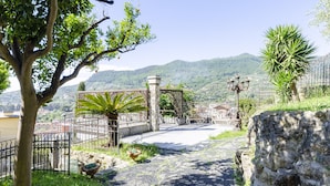 A paved pathway leading to a gated area with a view of a mountainous landscape. - JOIVY Splendid Villa With Orange Trees And Stunning View (Santa Margherita Ligure)