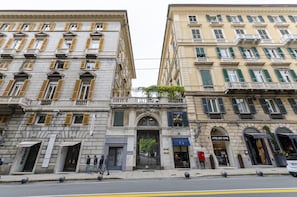 A street view of a building with multiple storefronts, including a visible shop named "Atelier Emé". - JOIVY Perfect Central Flat with Parking (Genoa)