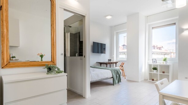 Une chambre moderne équipée d’un lit, d’une télévision, d’un bureau et d’une fenêtre donnant sur un beau paysage.