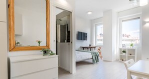 Et moderne soveværelse med seng, tv, skrivebord og et vindue med udsigt.