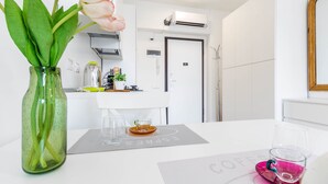 Une cuisine moderne avec des meubles blancs, une machine à café et un coin repas avec une table dressée pour deux personnes.