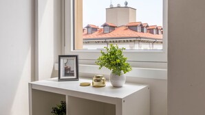 Un bureau blanc orné d’une photo encadrée, d’une petite plante dans un vase blanc et d’un pot décoratif.