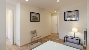 A hotel room with a bed, a chair, a table, a lamp, and two framed pictures on the wall. - JOIVY Bright 3-bedroom apartment in Santa Margherita (Santa Margherita Ligure)