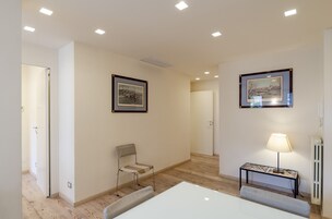 Una camera d'albergo con un letto, una sedia, un tavolo, una lampada e due quadri appesi al muro.