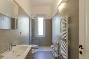 A modern bathroom with a bathtub, toilet, and shower.