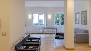 A modern, well-lit room with a wooden floor, a grey sofa, and a table with chairs. - JOIVY 3-Bedroom Family Apartment in Santa Margherita near Beach (Santa Margherita Ligure)