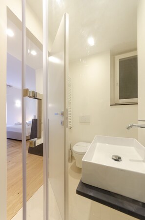 Een moderne badkamer met een wit wastafelmeubel, toilet en douchehoek.